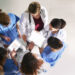 A group of doctors looking at a tablet Description automatically generated with low confidence